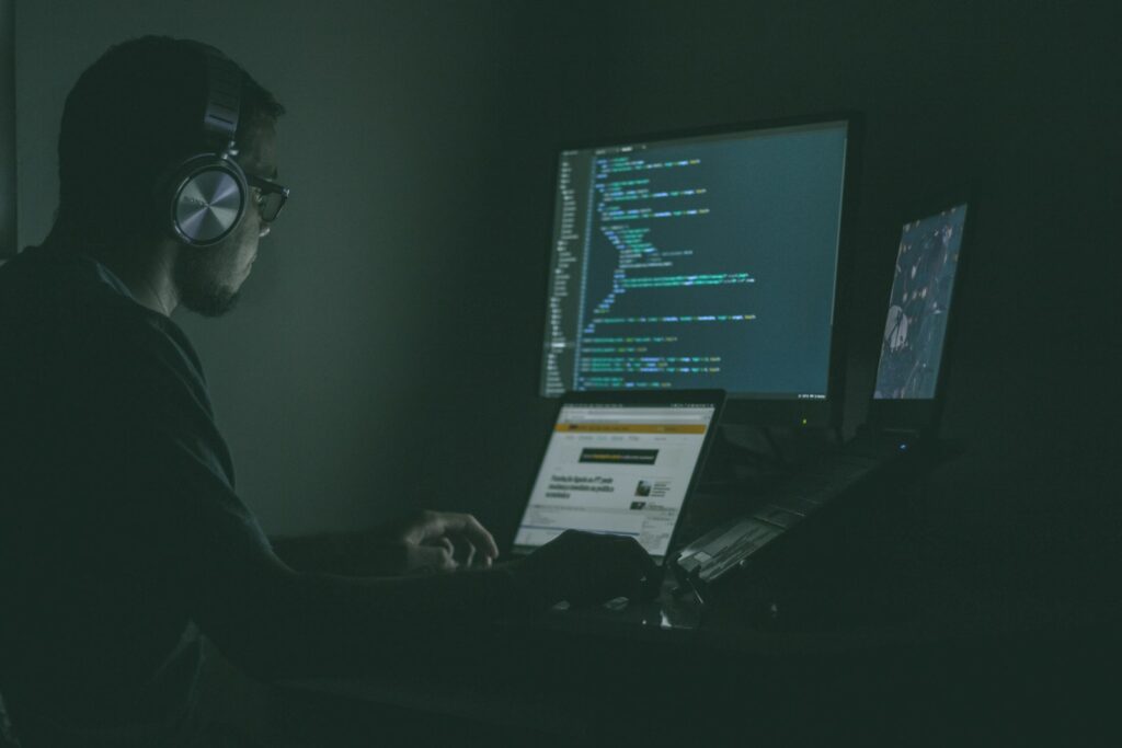 Werkplek met meerdere schermen waarop code en systeemmeldingen worden gevolgd
