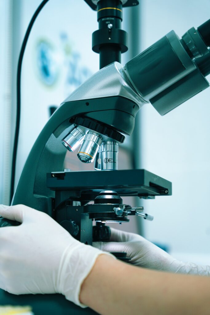 Gehandschoende hand bedient een microscoop in een laboratorium