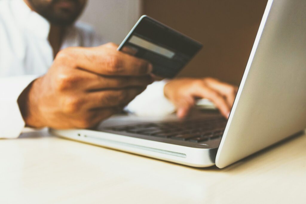 Persoon met bankpas achter een laptop tijdens een online betaling