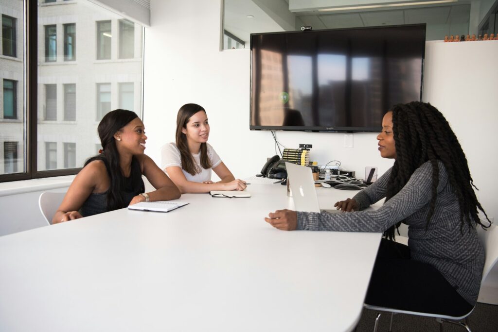 Drie mensen in gesprek aan een vergadertafel op kantoor