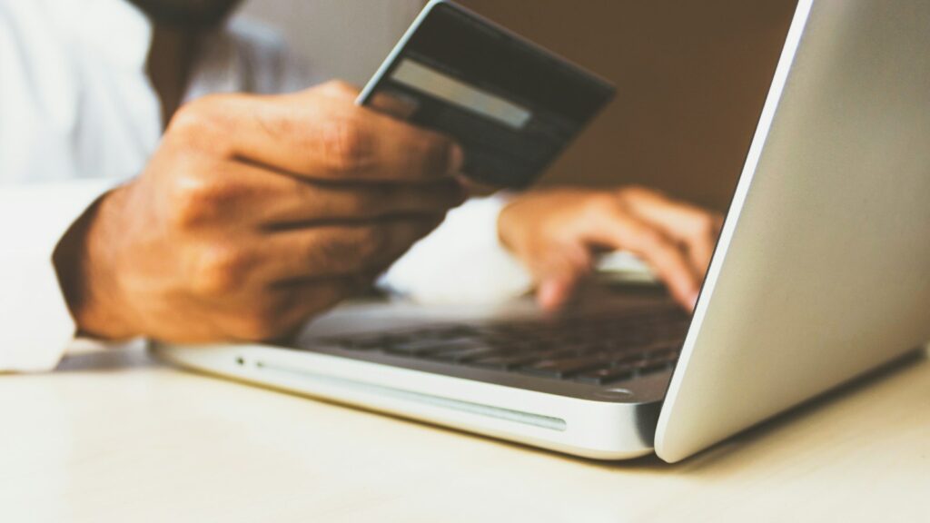 Persoon met laptop en betaalkaart tijdens online winkelen