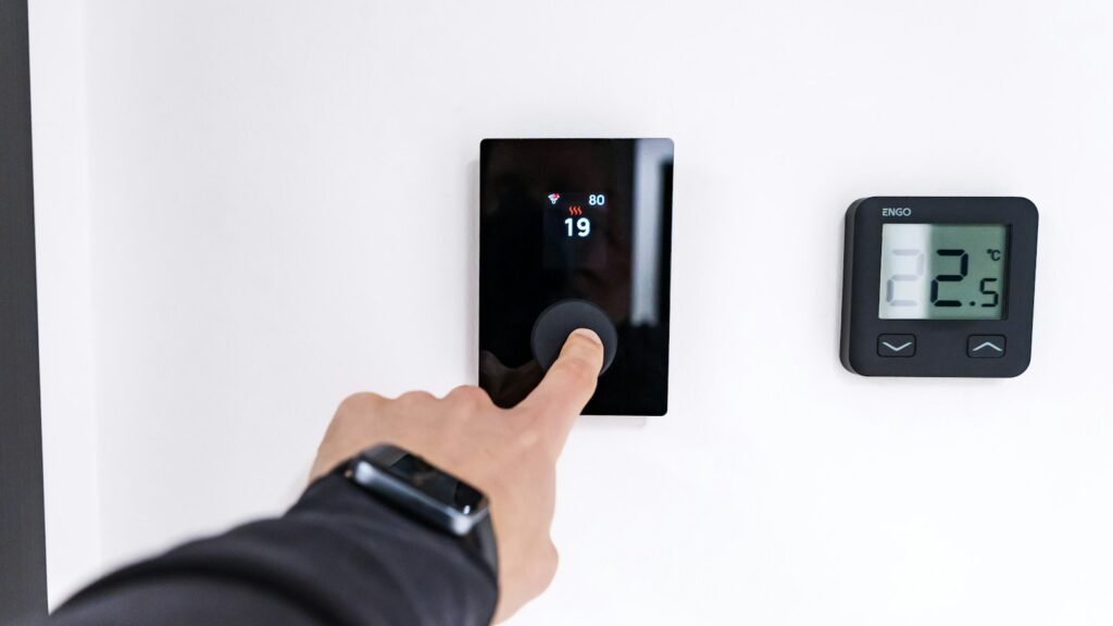 Vinger bedient een digitale thermostaat aan de muur