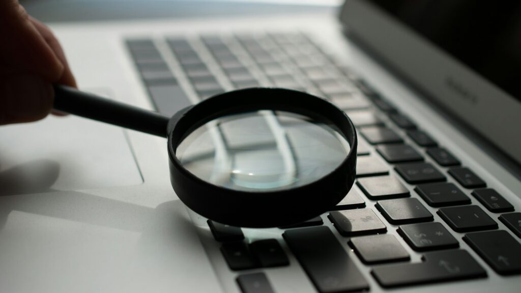 Vergrootglas naast een laptop met code